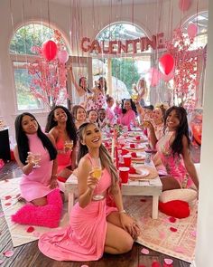 a group of women in pink dresses sitting at a table with plates and cups on it