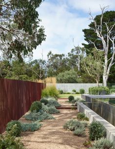 an outdoor garden with gravel and trees in the background