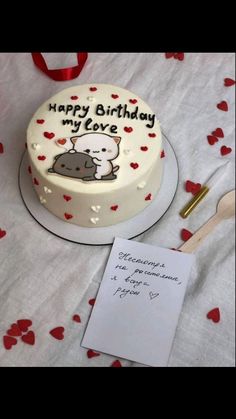 a birthday cake on a table with a note and pen next to it that says happy birthday my love