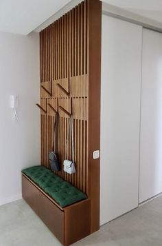 a green bench sitting in front of a wooden paneled wall with purses hanging on it