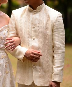 a man in a white suit standing next to a woman