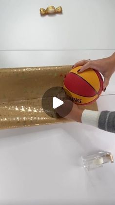 a person holding a basketball on top of a white counter next to a gold tray