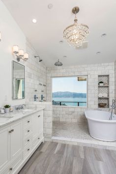 a large bathroom with white fixtures and wood flooring, along with an oval bathtub