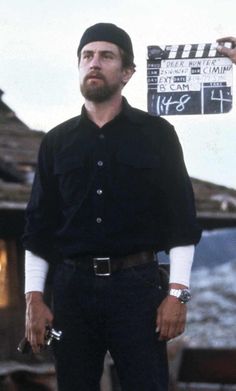 a man standing in front of a movie clapper with his hands on his hips