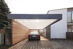 a car is parked under an awning in a driveway with brick pavers on the ground