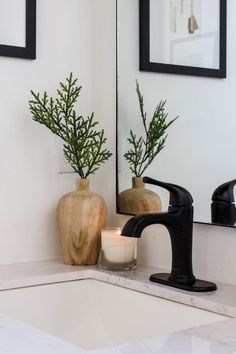 a bathroom sink with two vases and a candle