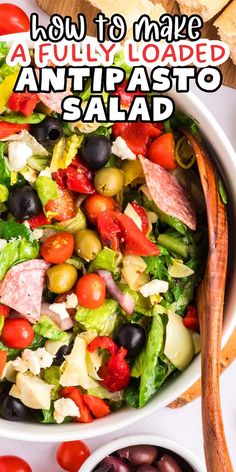 a salad in a bowl with olives, tomatoes and lettuce on the side