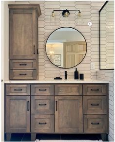 a bathroom vanity with wooden cabinets and a round mirror