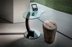 a tablet is sitting on a glass table next to a chair and footstool