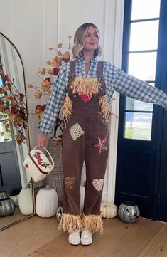 a woman standing in front of a mirror wearing brown overalls and holding her arms out