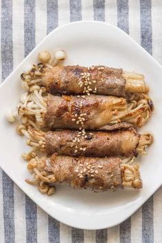 some food is on a white plate with chopsticks and sesame seed sprinkles