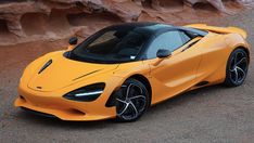 an orange sports car parked in front of some rocks