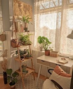 a room filled with lots of plants next to a white desk and chair in front of a window