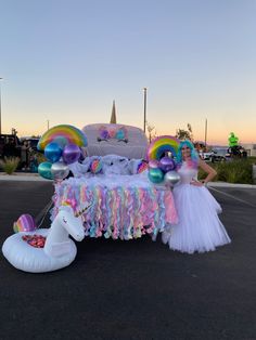 a woman standing in front of a float with a unicorn on it