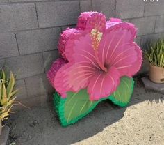 a large pink flower sitting on top of a green planter