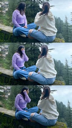 two women sitting on the ground next to each other in front of trees and water