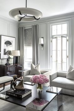 a living room filled with white furniture and lots of pink flowers on top of a coffee table