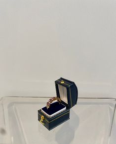 an open ring box sitting on top of a glass table next to a white wall