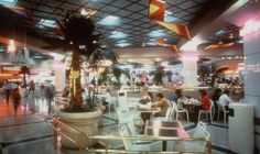 people are sitting at tables and eating in a restaurant with palm trees on the ceiling