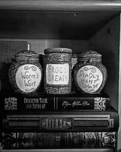 three jars with words on them are sitting on top of books in a bookcase