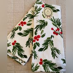 two white napkins with holly and red berries on them sitting next to each other