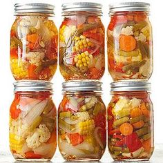 six jars filled with different types of vegetables