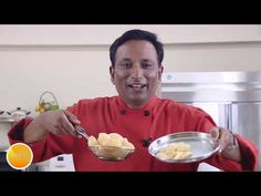 a man in a red chef's coat is holding a silver bowl with food on it