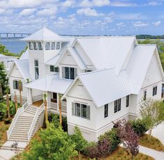 an aerial view of a white house with trees and water in the background