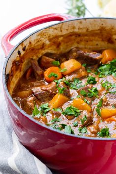 a red pot filled with stew and vegetables