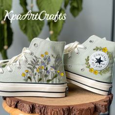 a pair of white shoes with flowers painted on them sitting on top of a piece of wood