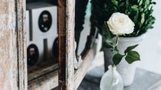 two vases filled with white flowers sitting on top of a wooden table next to an old window