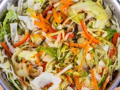 a salad with carrots, lettuce and other vegetables in a silver bowl