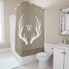 a shower curtain with antlers on it in a bathroom next to a toilet and sink