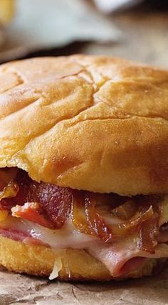 a close up of a sandwich on a piece of wax paper with bacon and cheese