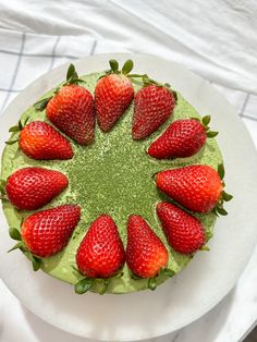 a green cake topped with strawberries on top of a white plate