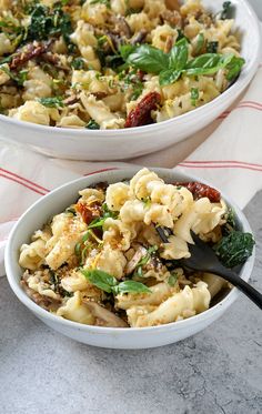 two white bowls filled with pasta and vegetables