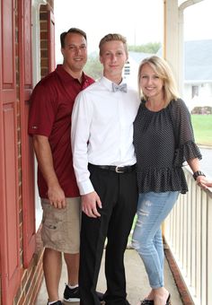 two men and a woman are standing on the porch with their arms around each other