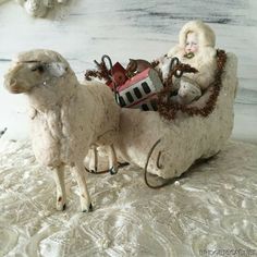 a white sheep with a baby in it's sleigh sitting on a bed