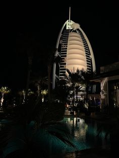 the burj building is lit up at night, with palm trees around it