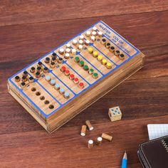 a wooden board game sitting on top of a table next to a notebook and pen