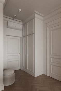 an empty room with wooden floors and white walls, along with a round ottoman in the middle