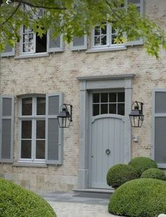 a stone house with grey shutters and gray doors