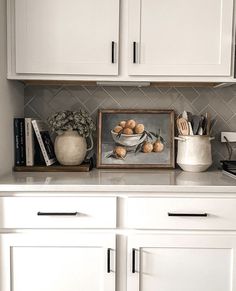 a kitchen with white cupboards and countertops has an image of apples in a bowl