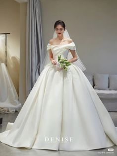 a woman in a white wedding dress standing next to a couch