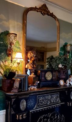 there is a mirror on the wall above a dresser with an antique clock and other items