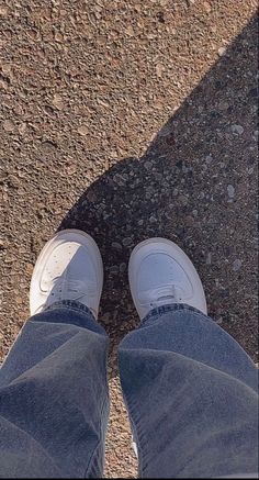 a person standing on the ground with their feet in the air and wearing white shoes