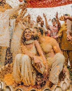 people are throwing colored powder on each other in the air as they pose for a photo