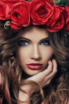 a beautiful woman with long hair and red roses on her head is posing for the camera