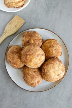 several donuts on a plate next to a wooden spoon