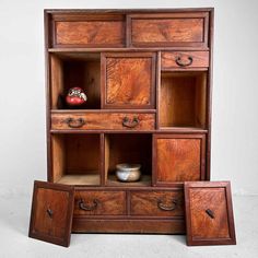 an old wooden shelf with drawers and two bowls on the bottom one is open to reveal other items